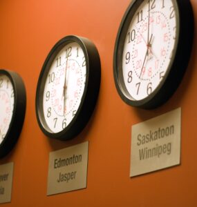 Parede laranja com vários relógios mostrando diferentes fusos horários.