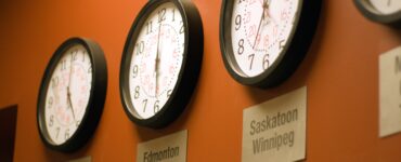 Parede laranja com vários relógios mostrando diferentes fusos horários.