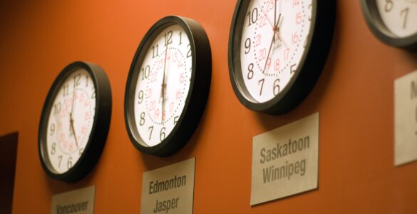 Parede laranja com vários relógios mostrando diferentes fusos horários.