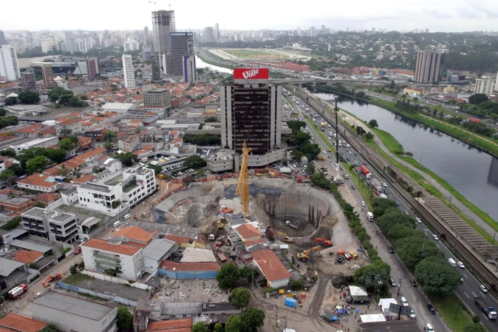 Vista aérea do local do desabamento nas obras da Estação Pinheiros do Metrô de São Paulo, mostrando grande cratera e maquinário no entorno.