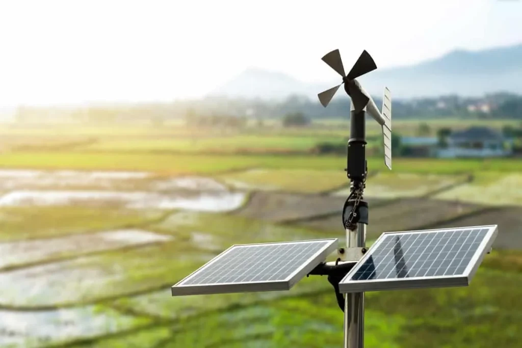 Estação meteorológica automática equipada com painéis solares e anemômetro em área agrícola para monitoramento climático.