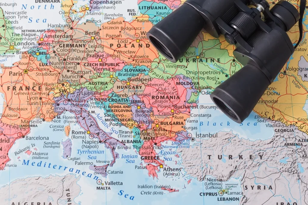Mapa político da Europa com países coloridos e um par de binóculos pretos apoiado sobre a região da Ucrânia, Romênia e Bulgária.