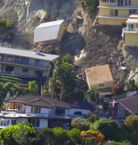 Foto de deslizamento de terra levando várias casas abaixo.