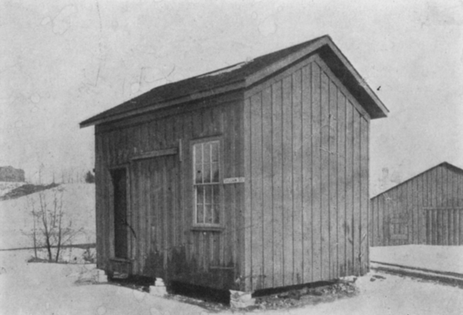 Foto preto e branco de uma cabana de madeira, a Vulcan Street Plant, primeira usina hidrelétrica dos EUA.