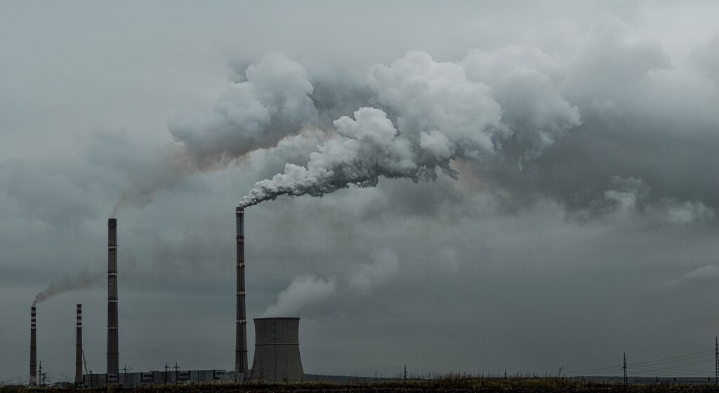 Imagem de uma fábrica soltando nuvens de fumaça no céu.
