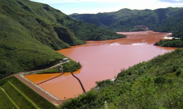 Tipos de materiais de barragens: foto de uma barragem com uma água barrosa, cercada de vegetação.