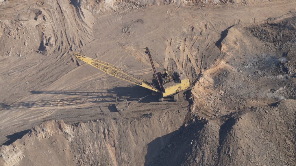Imagem aérea de uma mina, com uma escavadeira no centro.