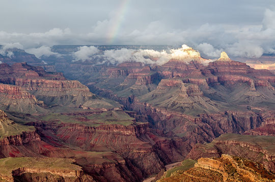 Imagem do Grand Canyon visto de cima, com nuvens ao redor dos picos.