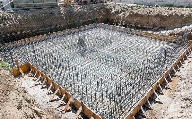 Foto de um projeto de fundações em solo, em formato retangular, com estacas de metal espetadas na estrutura.