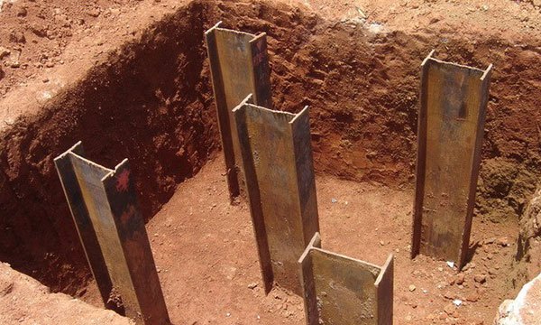 Foto de fundações por estaca numa escavação de terra.