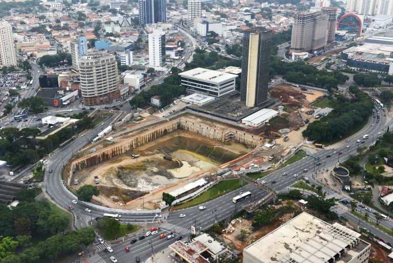 Vista aérea da obra do Piscinão do Paço, em São Bernardo do Campo. Trata-se de uma escavação em formato de polígono no meio da cidade, com uma rodovia passando em volta.