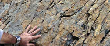 Foto de mão tocando rocha com clivagem