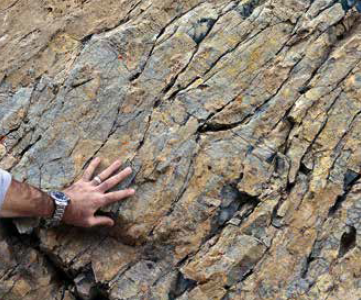 Foto de mão tocando rocha com clivagem
