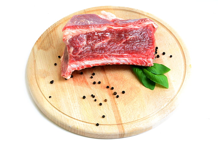 Imagem de uma tábua com carne crua em cima, e folhas de louro, simbolizando uma dieta de proteínas.