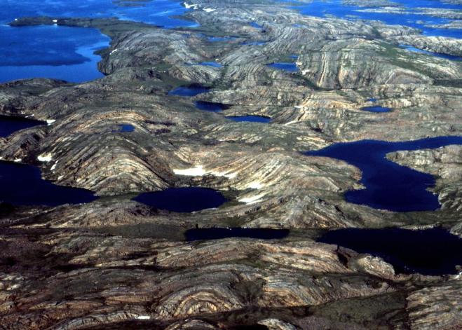 Foto de várias formações de rochas que passaram por processo de deformação com o tempo, com lagoas entre elas.