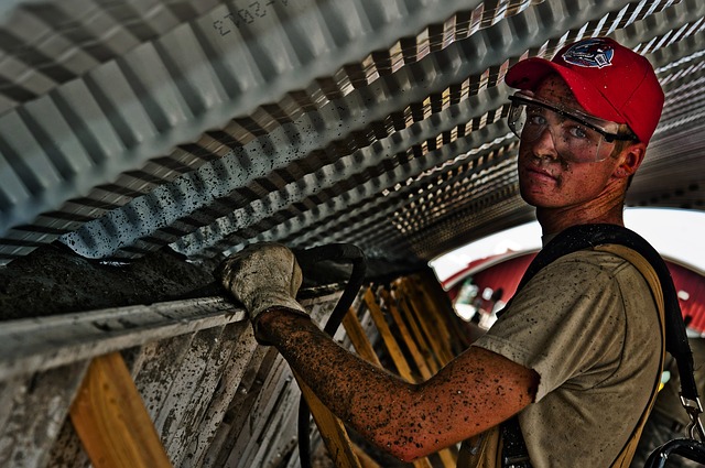 Foto de um trabalhador da construção civil do Brasil olhando para a câmera enquanto ajusta uma estrutura de concreto pré-moldado.