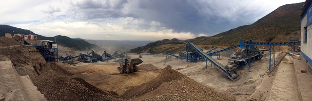 Foto da infraestrutura de uma mina a céu aberto em obras, com máquinas e equipamentos movendo a terra.