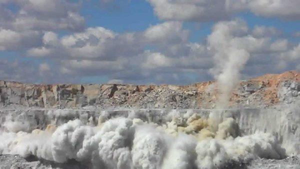 Foto de fumaça subindo em uma mina a céu aberto, por causa dos explosivos usados nas rochas.