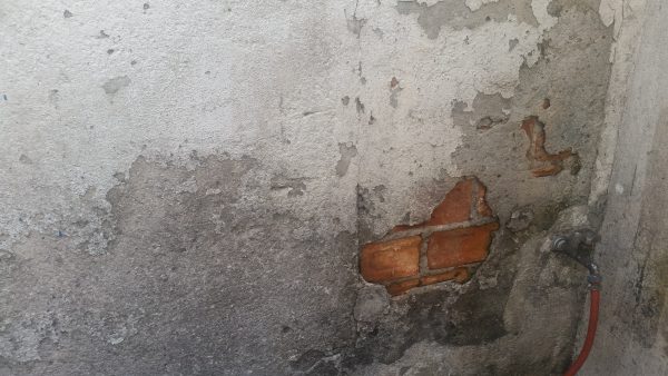 Imagem de patologia em um projeto de alvenaria, com os tijolos aparecendo por trás do concreto.