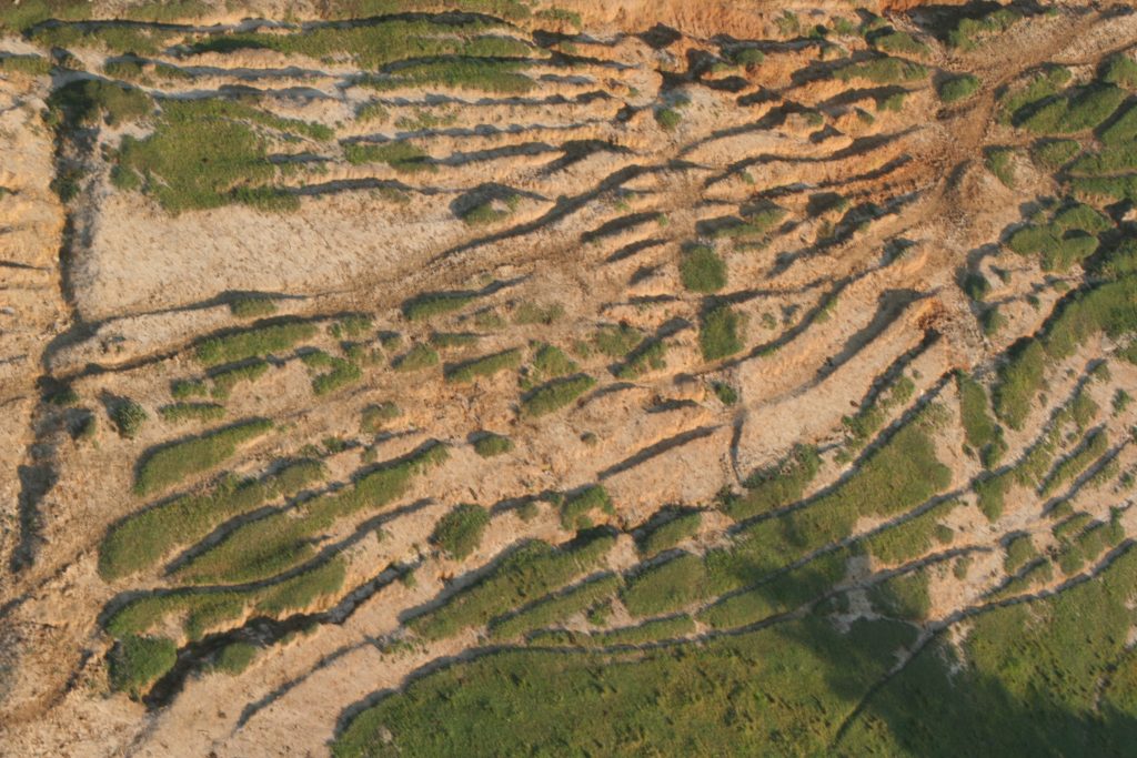 Foto aérea do processo de erosão numa área em Piracicaba, com diversos trechos marrons sem vegetação.