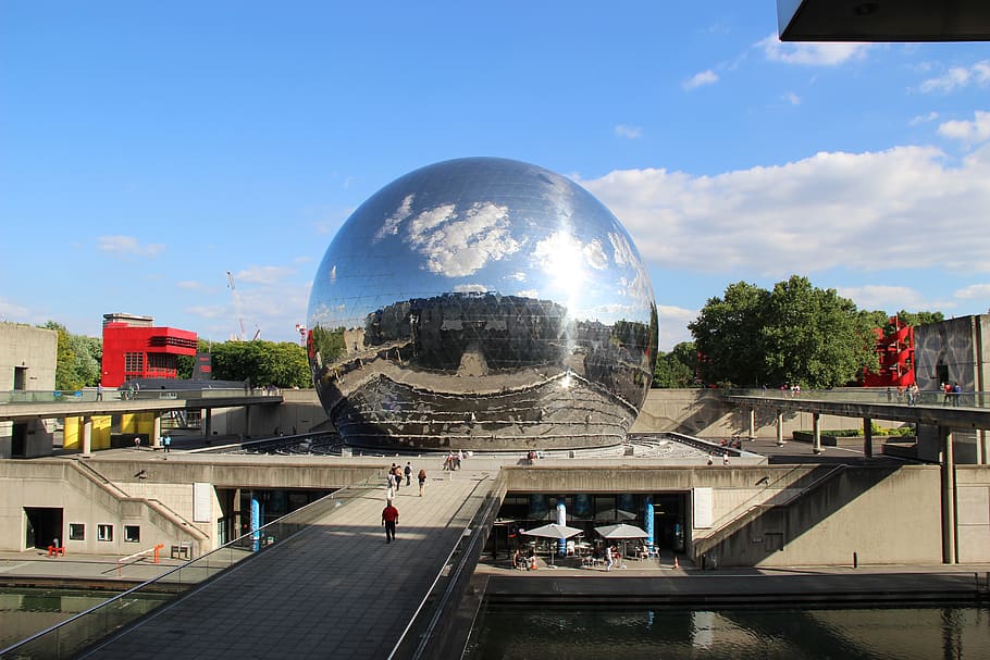 Foto de La Géode, uma das maiores cúpulas geodésicas do mundo, e sua superfície espelhada. Ao redor, um parque na França.