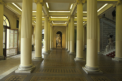Foto de um corredor do Museu Paulista, com várias colunas brancas e uma estátua ao fundo.