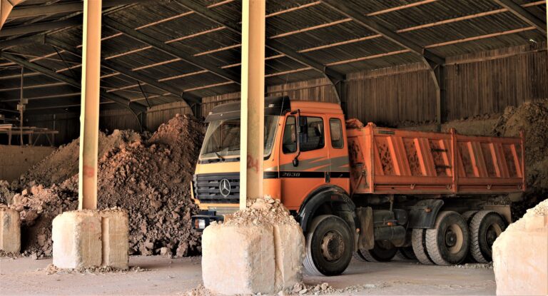 Foto de um caminhão estacionado ao lado de uma pilha de resíduos de construção.