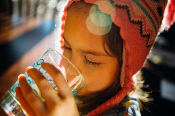 Foto de uma criança bebendo água de um copo.