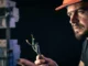 Eletricista com capacete de proteção analisando fios elétricos expostos durante manutenção