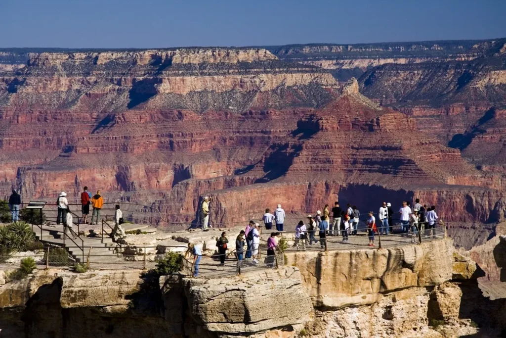 Visitantes observam as camadas geológicas coloridas do Grand Canyon a partir de um mirante turístico nos Estados Unidos