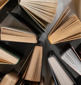 Vista aérea de vários livros abertos dispostos em círculo sobre superfície clara