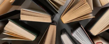 Vista aérea de vários livros abertos dispostos em círculo sobre superfície clara