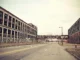 Vista de uma rua deserta cercada por prédios industriais abandonados em Detroit, com janelas quebradas e grafites nas paredes