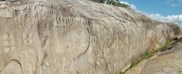Inscrições rupestres entalhadas na Pedra do Ingá, um grande rochedo na Paraíba, com símbolos geométricos e abstratos gravados na superfície.