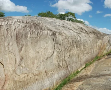 Inscrições rupestres entalhadas na Pedra do Ingá, um grande rochedo na Paraíba, com símbolos geométricos e abstratos gravados na superfície.