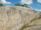 Inscrições rupestres entalhadas na Pedra do Ingá, um grande rochedo na Paraíba, com símbolos geométricos e abstratos gravados na superfície.