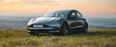 Tesla Model 3 preto estacionado em campo aberto durante o pôr do sol, simbolizando inovação, sustentabilidade e mobilidade elétrica