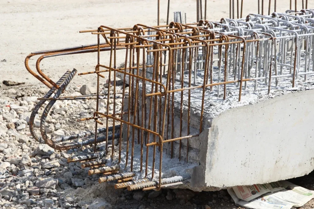 Estrutura de concreto armado em obra com vergalhões de aço expostos, formando armação para sustentação estrutural.