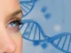 Close no rosto de uma mulher com olhos azuis em primeiro plano, ao fundo representação de hélice de DNA em cor azul.