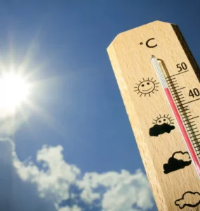 Termômetro de madeira marca temperatura próxima a 40 °C sob sol forte em céu azul, simbolizando onda de calor.