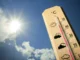 Termômetro de madeira marca temperatura próxima a 40 °C sob sol forte em céu azul, simbolizando onda de calor.