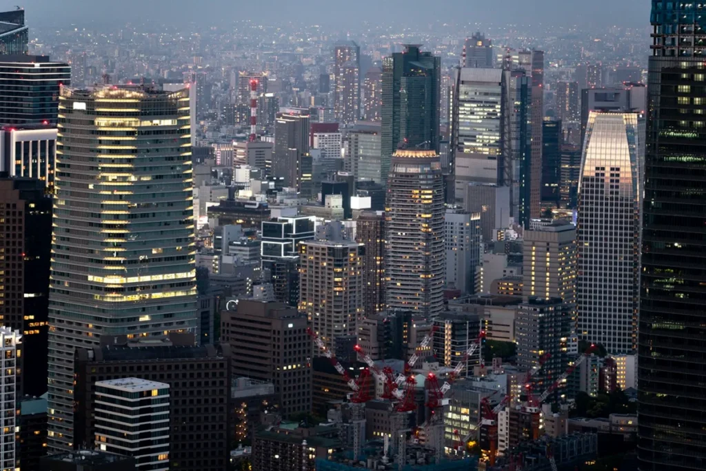 Vista panorâmica de Tóquio à noite, com arranha-céus iluminados, arquitetura moderna e intensa densidade urbana, simbolizando tecnologia e inovação.