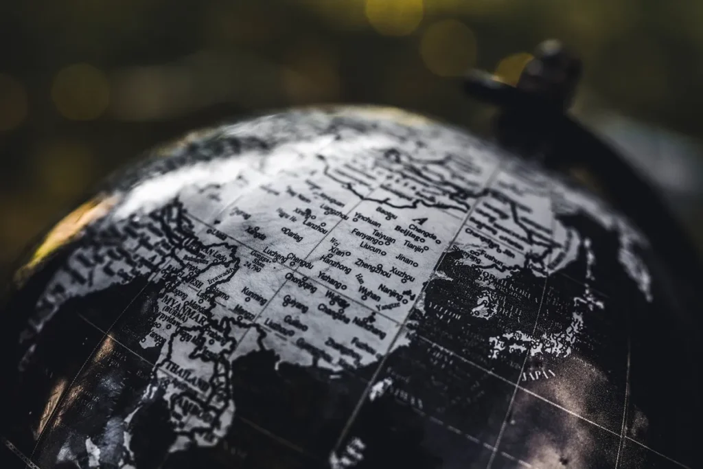 Globo terrestre em preto e branco mostrando países da Ásia, como China, Japão, Tailândia e Myanmar, simbolizando estudos geopolíticos e análise internacional.