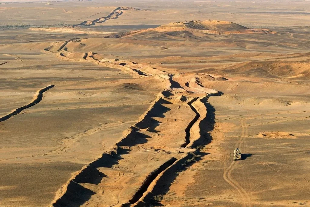 Vista aérea de uma região árida com grandes fendas e erosões no solo, evidenciando os efeitos da desertificação e da degradação ambiental.