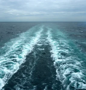 Rastro deixado por embarcação em movimento sobre o oceano, mostrando a formação de correntes marítimas.