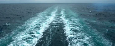 Rastro deixado por embarcação em movimento sobre o oceano, mostrando a formação de correntes marítimas.