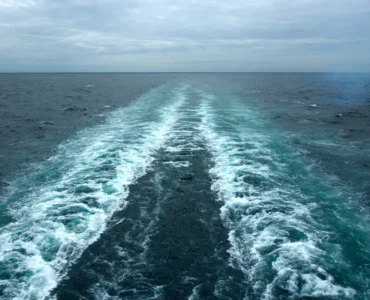 Rastro deixado por embarcação em movimento sobre o oceano, mostrando a formação de correntes marítimas.