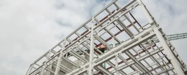 Estrutura metálica de edifício em construção, mostrando vigas de aço e elementos de sustentação contra o céu nublado.