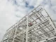 Estrutura metálica de edifício em construção, mostrando vigas de aço e elementos de sustentação contra o céu nublado.