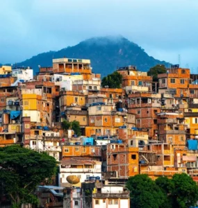Vista colorida de uma favela brasileira com casas construídas em morros, mostrando edificações irregulares, telhados variados e vegetação ao redor.
